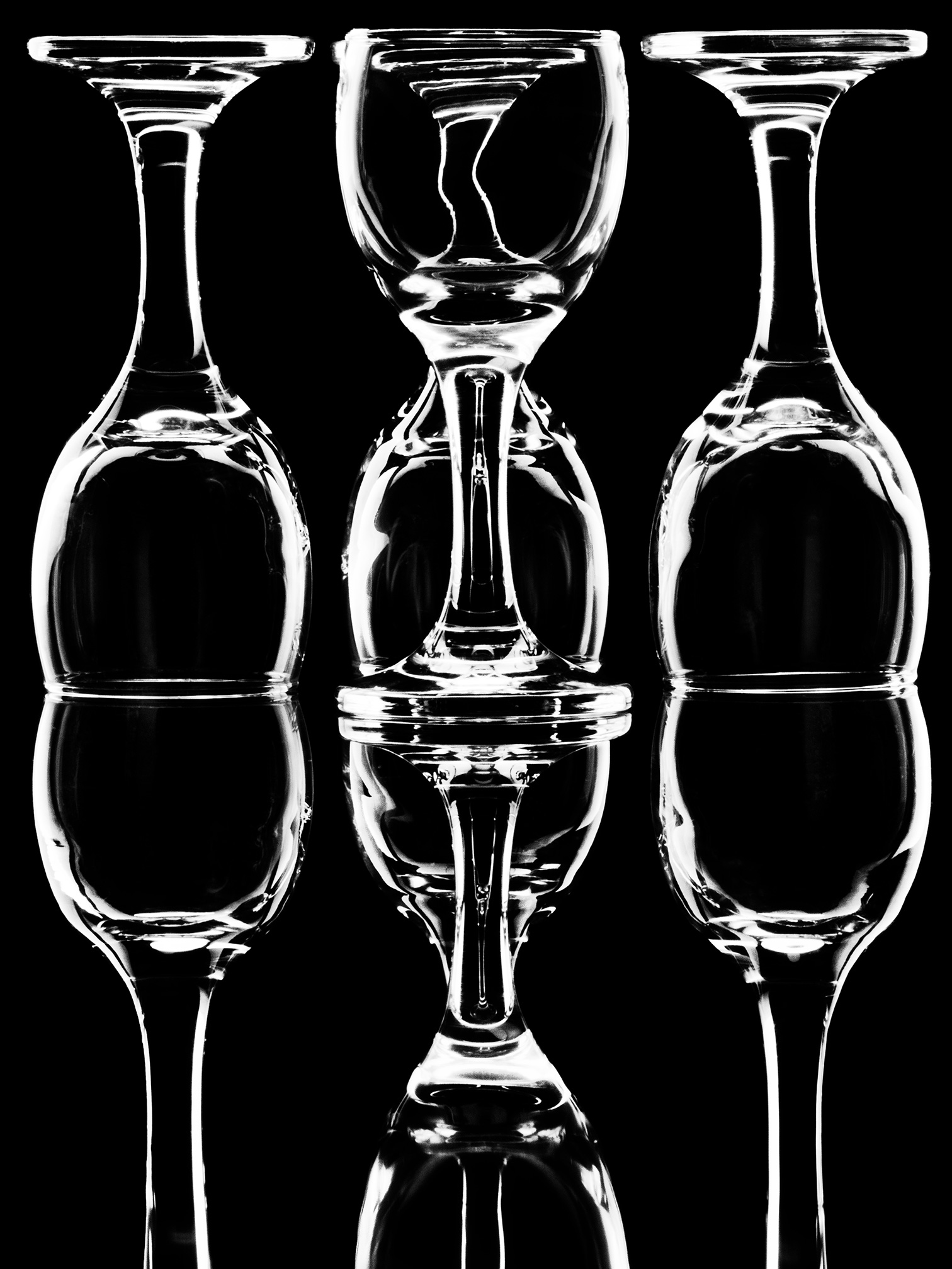 Set of Glassware photographed to show reflection on clear surface, dark background